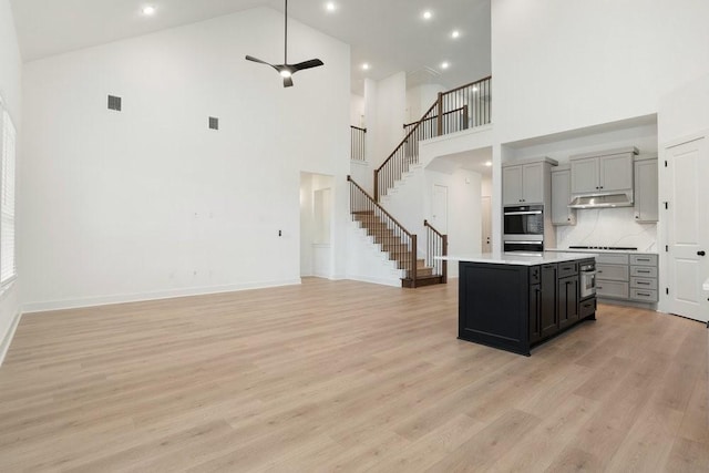 kitchen featuring gray cabinets, tasteful backsplash, a center island, and high vaulted ceiling