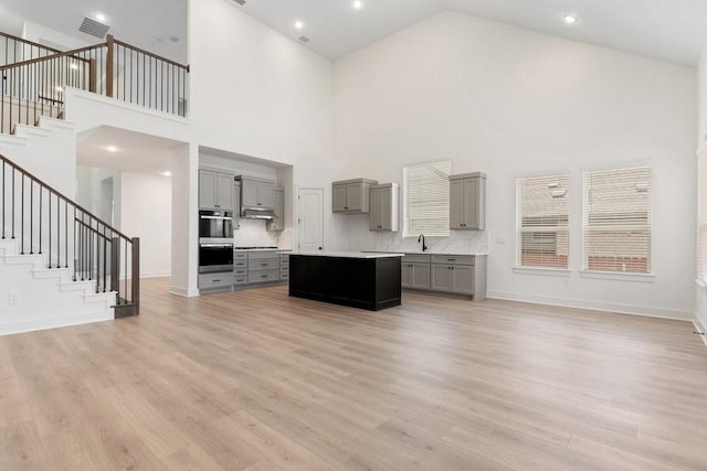 kitchen with tasteful backsplash, a towering ceiling, a kitchen island, and gray cabinetry