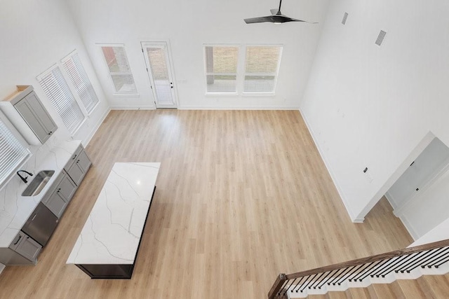 unfurnished living room with sink, light hardwood / wood-style flooring, and ceiling fan