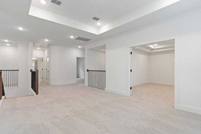 unfurnished room featuring a raised ceiling and light colored carpet