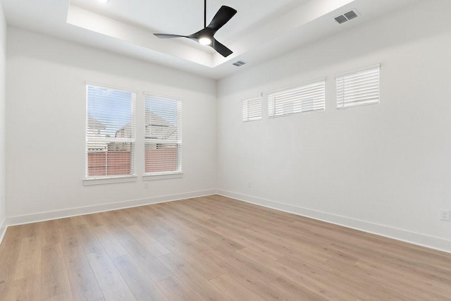 spare room featuring a tray ceiling, light hardwood / wood-style floors, and ceiling fan