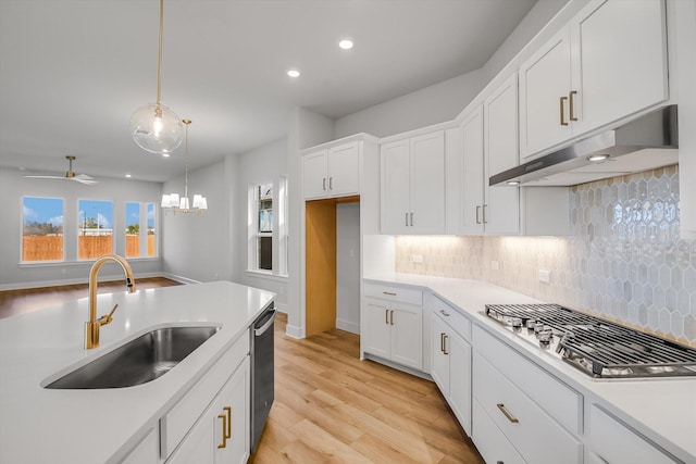 kitchen featuring white cabinets, appliances with stainless steel finishes, decorative light fixtures, light hardwood / wood-style floors, and sink