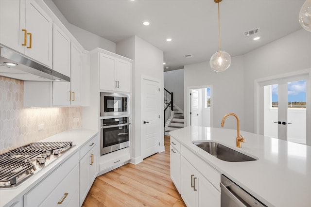 kitchen featuring sink, decorative light fixtures, white cabinets, decorative backsplash, and stainless steel appliances