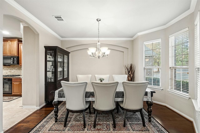 dining room with crown molding, a chandelier, and dark hardwood / wood-style flooring