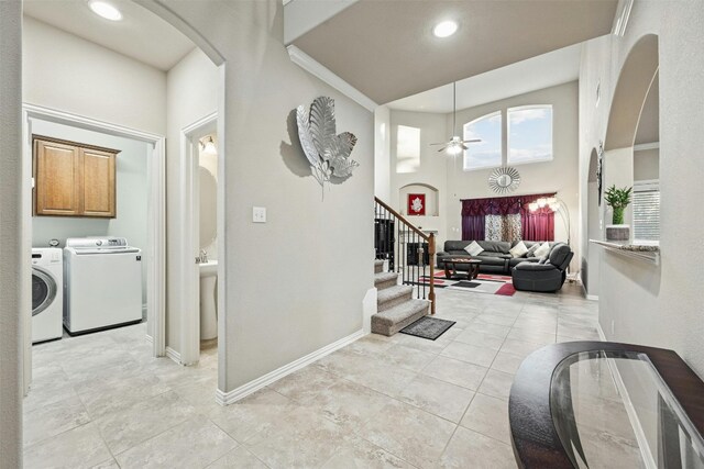 hall with crown molding, light tile patterned flooring, washing machine and dryer, and a towering ceiling