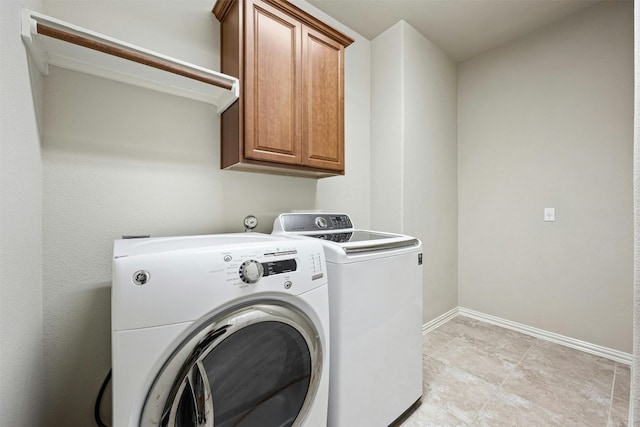 clothes washing area with cabinets and washing machine and clothes dryer