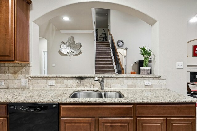 kitchen with decorative backsplash, dishwasher, sink, and light stone counters