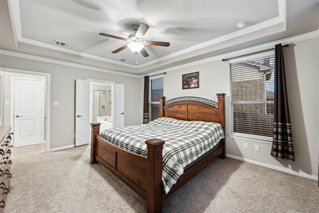 carpeted bedroom with ceiling fan, ornamental molding, a tray ceiling, and ensuite bath