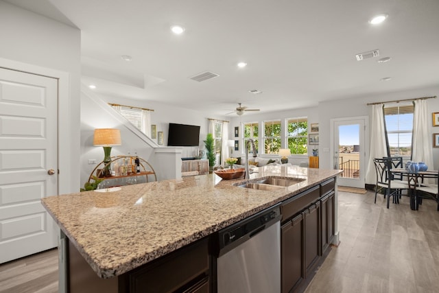 kitchen with stainless steel dishwasher, sink, light hardwood / wood-style flooring, and a kitchen island with sink