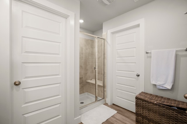 bathroom with a shower with door and hardwood / wood-style flooring