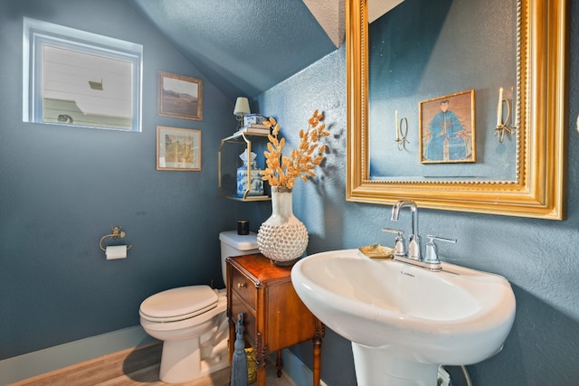 bathroom featuring sink, toilet, wood-type flooring, and vaulted ceiling