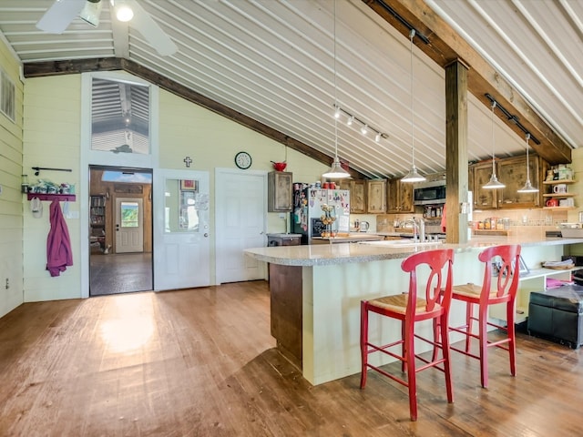 kitchen featuring hardwood / wood-style flooring, a breakfast bar area, fridge with ice dispenser, high vaulted ceiling, and ceiling fan