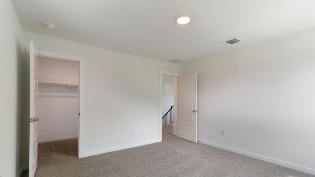 unfurnished bedroom with a walk in closet, a closet, and carpet