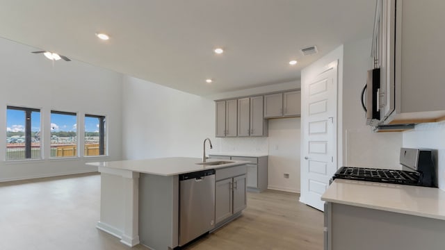 kitchen with appliances with stainless steel finishes, sink, an island with sink, light hardwood / wood-style floors, and gray cabinets