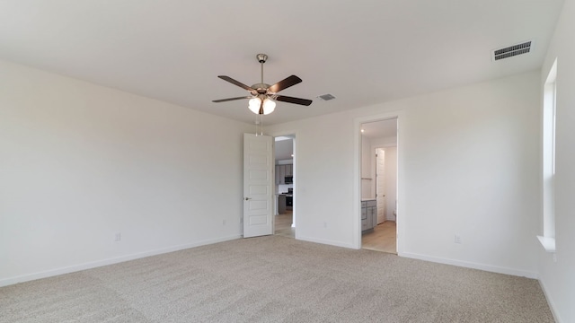 unfurnished bedroom featuring light carpet, ensuite bathroom, and ceiling fan