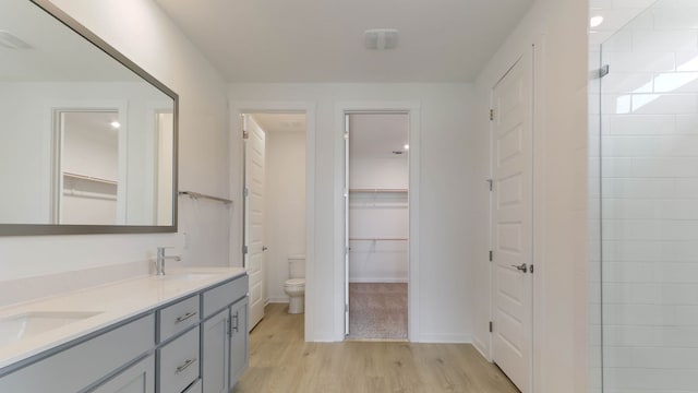 bathroom featuring toilet, hardwood / wood-style floors, vanity, and tiled shower