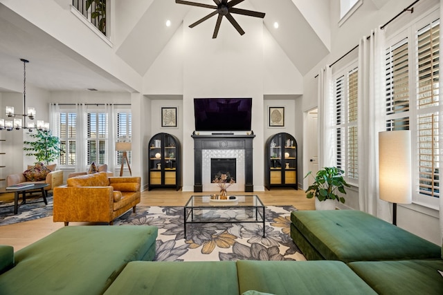 living room with light hardwood / wood-style flooring, a tiled fireplace, and high vaulted ceiling