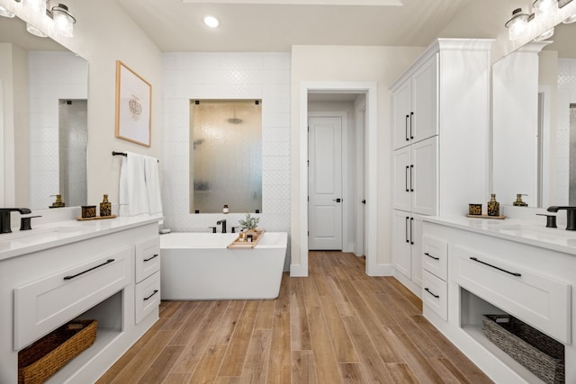 bathroom featuring vanity, wood-type flooring, and plus walk in shower