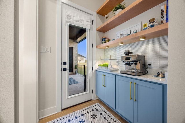 bar with light hardwood / wood-style floors and blue cabinets