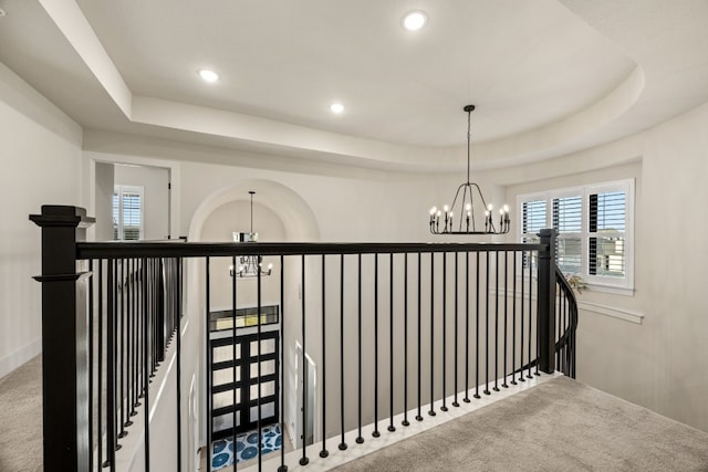 corridor featuring a notable chandelier, carpet flooring, and a tray ceiling