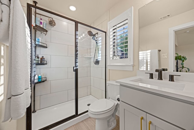 bathroom with vanity, an enclosed shower, toilet, and wood-type flooring