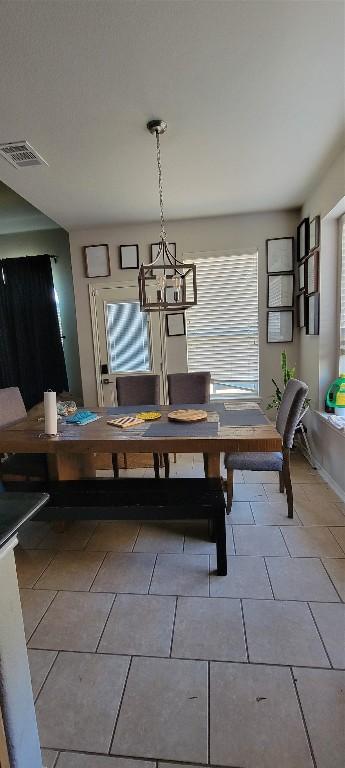 tiled dining room featuring a notable chandelier