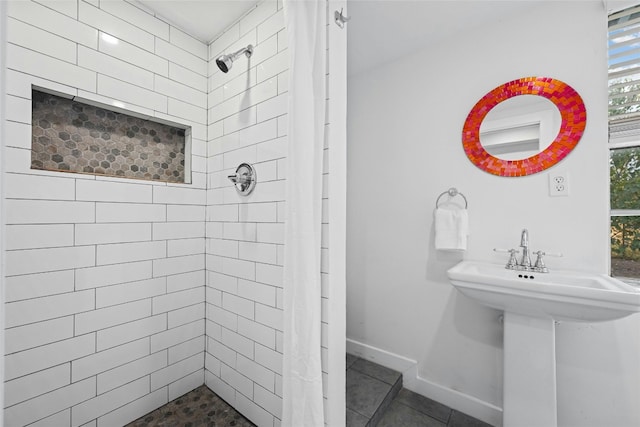 full bathroom with tile patterned flooring, a sink, a tile shower, and baseboards