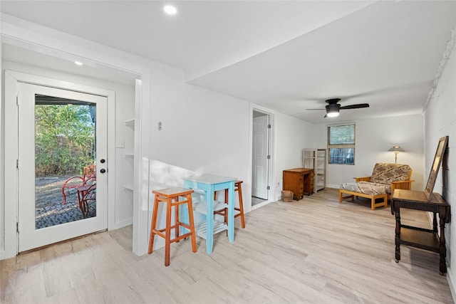 living area with ceiling fan, plenty of natural light, wood finished floors, and baseboards