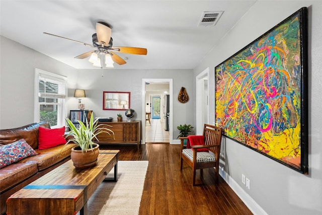 living area with a ceiling fan, baseboards, visible vents, and wood finished floors