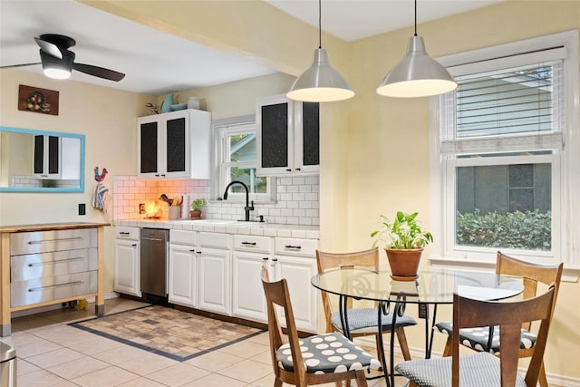 kitchen with tasteful backsplash, white cabinets, tile countertops, pendant lighting, and a sink