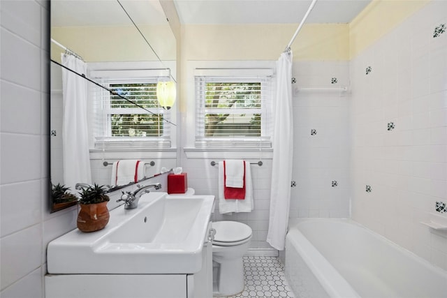 full bath with toilet, tile patterned floors, shower / bath combo with shower curtain, vanity, and tile walls