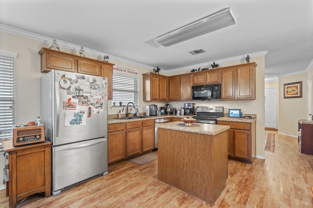 kitchen with a kitchen island, appliances with stainless steel finishes, light hardwood / wood-style floors, crown molding, and sink