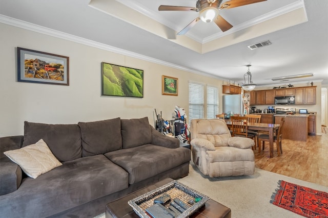 living room with ceiling fan, crown molding, a tray ceiling, and hardwood / wood-style floors