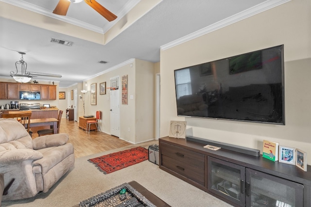 living room with ornamental molding, light wood-type flooring, and ceiling fan