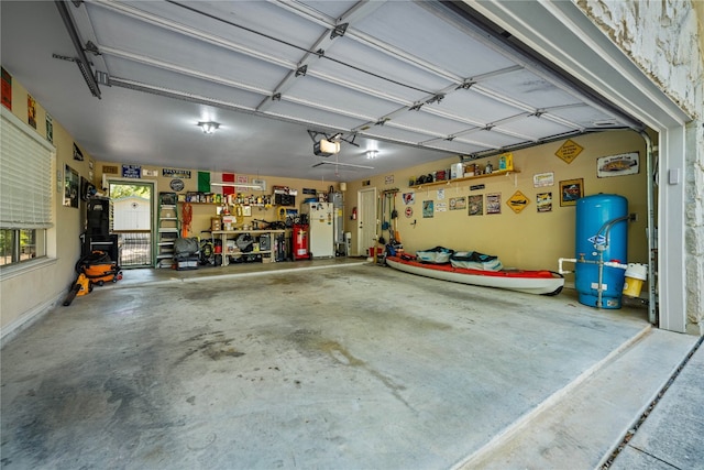 garage with a workshop area, a garage door opener, and white refrigerator