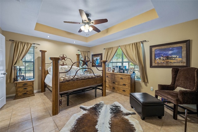 tiled bedroom with a raised ceiling and ceiling fan