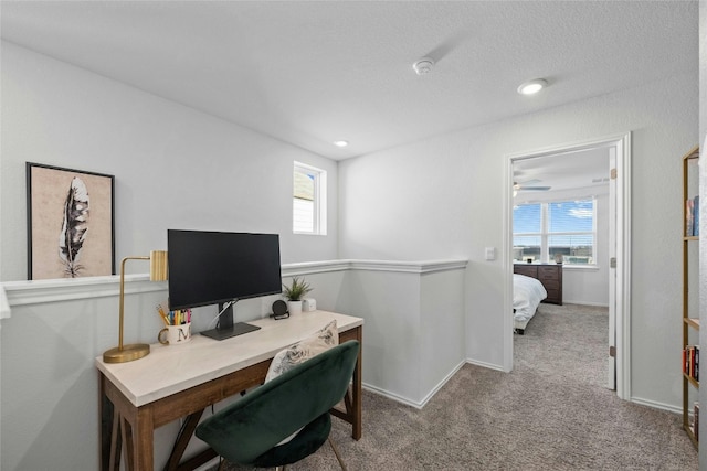 carpeted office space with a textured ceiling, a healthy amount of sunlight, and ceiling fan