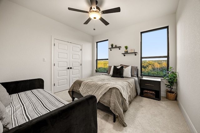 carpeted bedroom featuring a closet, ceiling fan, and multiple windows