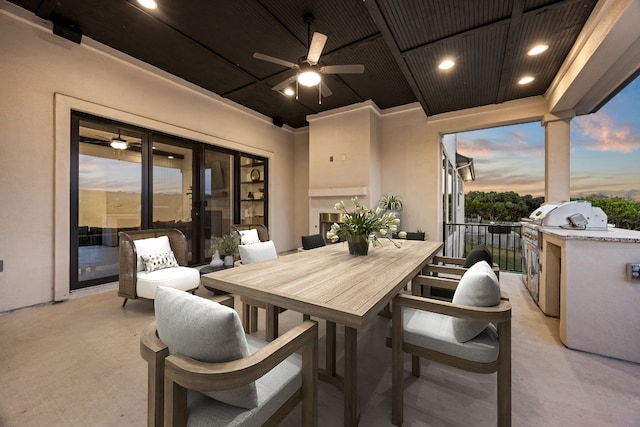 patio terrace at dusk featuring an outdoor kitchen, a grill, and ceiling fan