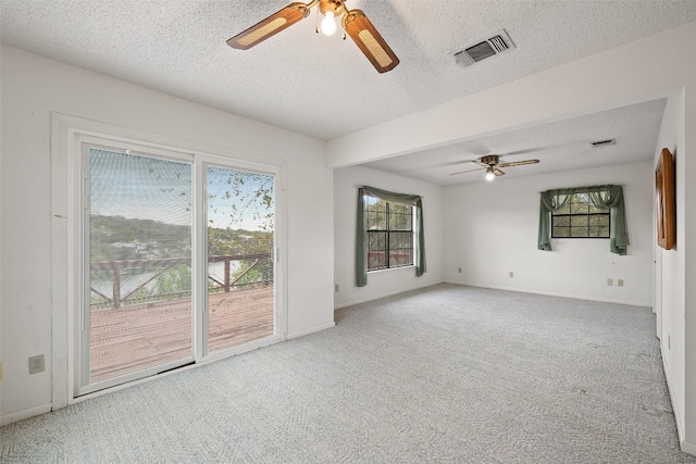 unfurnished living room featuring ceiling fan, a textured ceiling, and light colored carpet