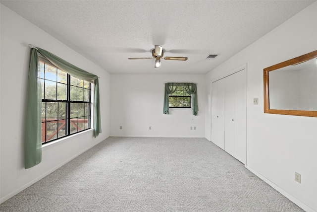 empty room featuring a textured ceiling, light colored carpet, and ceiling fan