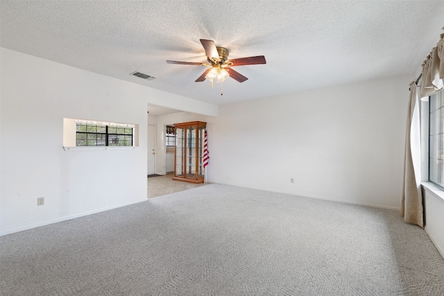 spare room featuring light carpet, a textured ceiling, and ceiling fan