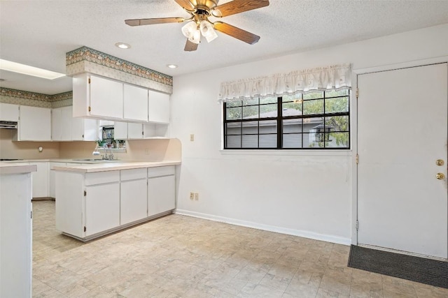 502 E Ave, Marble Falls, TX 78654 - kitchen with white cabinets, a sink, light countertops, a peninsula, and a ceiling fan
