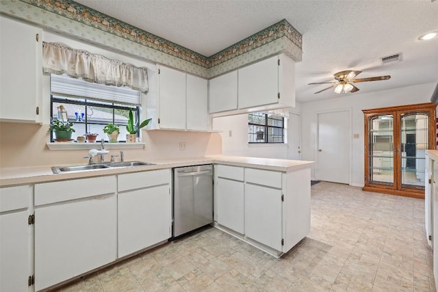 502 E Ave, Marble Falls, TX 78654 - kitchen with stainless steel dishwasher, a sink, a peninsula, a textured ceiling, and light countertops