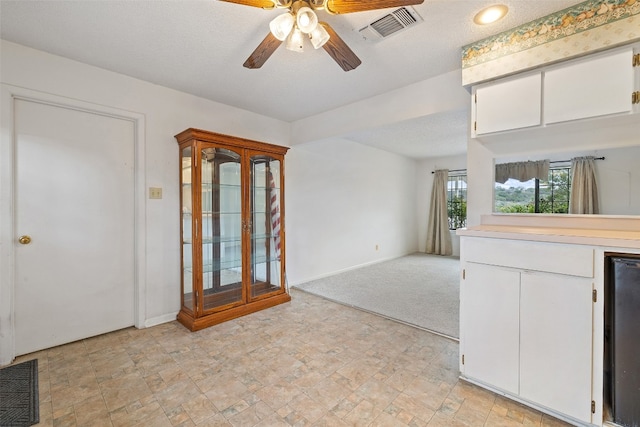 interior space featuring a textured ceiling, ceiling fan, white cabinets, wine cooler, and light colored carpet