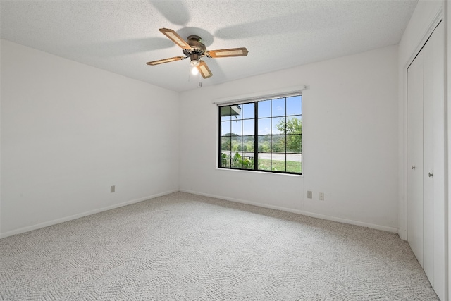 unfurnished bedroom featuring carpet, a textured ceiling, a closet, and ceiling fan