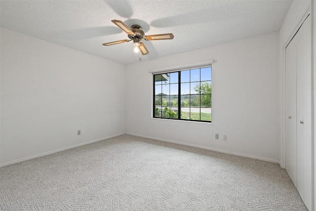 502 E Ave, Marble Falls, TX 78654 - unfurnished bedroom featuring a closet, light colored carpet, a textured ceiling, ceiling fan, and baseboards