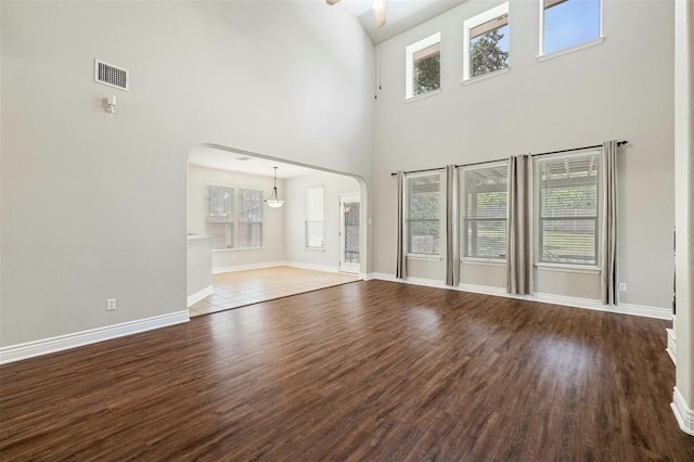 unfurnished living room featuring a healthy amount of sunlight, hardwood / wood-style flooring, and a high ceiling