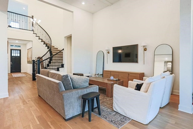 living room featuring an inviting chandelier, light hardwood / wood-style flooring, and a high ceiling