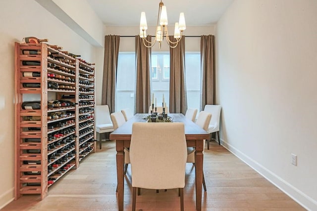 dining area with light hardwood / wood-style flooring and an inviting chandelier